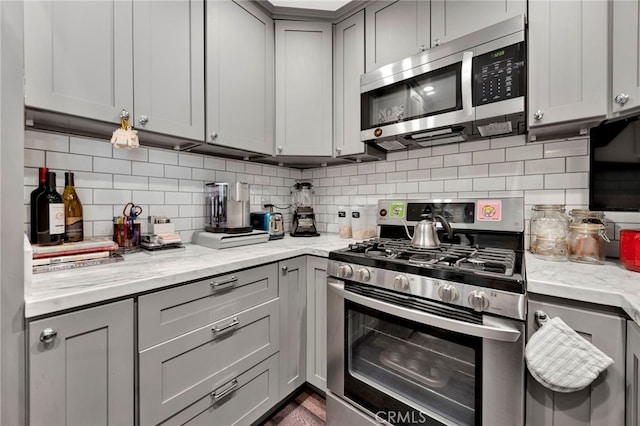 1118 Valencia St Unit 120, Los Angeles, CA 90015 - kitchen featuring stainless steel appliances, gray cabinetry, tasteful backsplash, and light stone counters