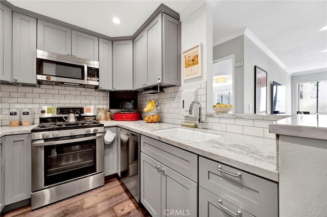 1118 Valencia St Unit 120, Los Angeles, CA 90015 - kitchen with appliances with stainless steel finishes, gray cabinets, ornamental molding, decorative backsplash, and light wood-style floors