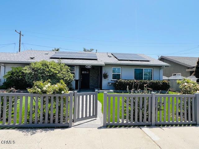 1900 Piedmont St, Oxnard, CA 93035 - view of front of home with a fenced front yard, solar panels, stucco siding, and a gate