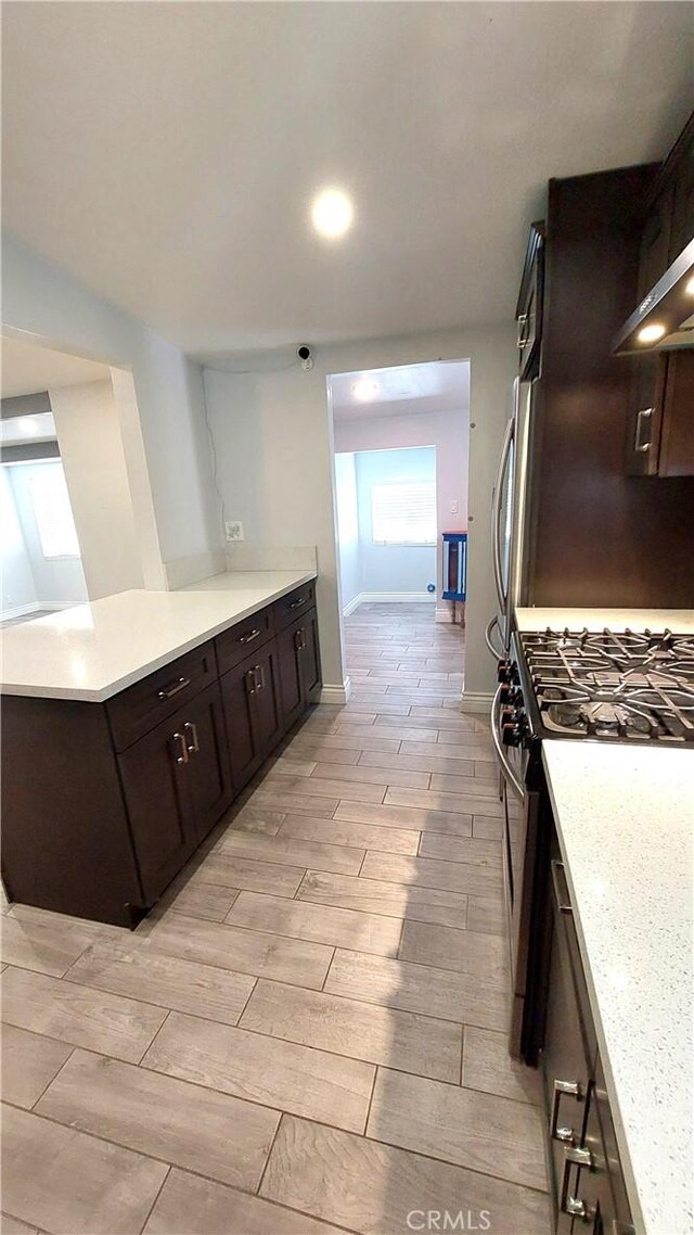 8649 Cantaloupe Ave, Panorama City, CA 91402 - kitchen featuring gas range, dark brown cabinetry, light countertops, and a peninsula