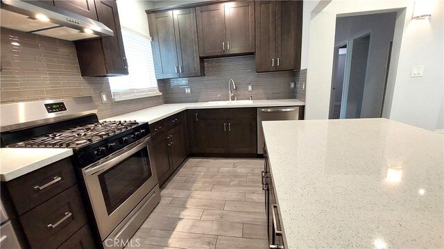 8649 Cantaloupe Ave, Panorama City, CA 91402 - kitchen with stainless steel appliances, under cabinet range hood, dark brown cabinetry, and backsplash