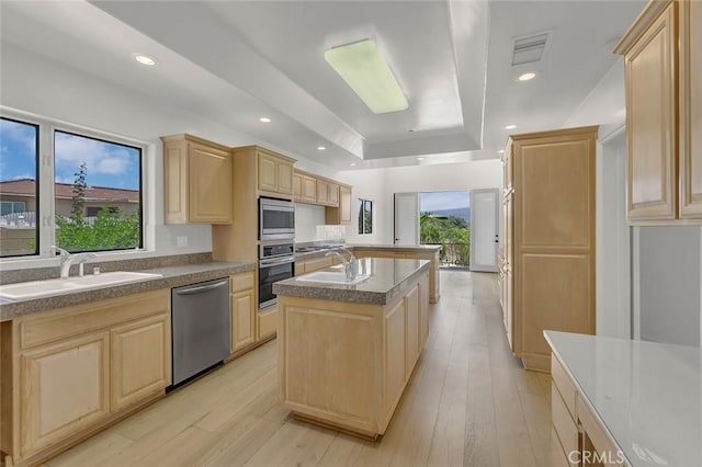 6041 Calle Mirador, Yorba Linda, CA 92886 - kitchen featuring appliances with stainless steel finishes, light brown cabinets, a kitchen island with sink, light wood finished floors, and a raised ceiling