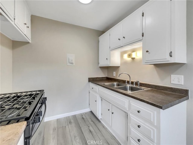 1920 N H St Unit 251, Oxnard, CA 93036 - kitchen with gas range, light wood finished floors, dark countertops, and white cabinetry