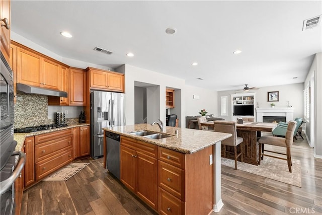 42639 Biscay, Lancaster, CA 93536 - kitchen featuring appliances with stainless steel finishes, dark wood finished floors, a ceiling fan, a center island with sink, and light stone counters