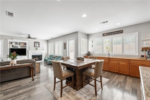 42639 Biscay, Lancaster, CA 93536 - dining area featuring healthy amount of natural light, light wood-type flooring, a ceiling fan, a glass covered fireplace, and recessed lighting
