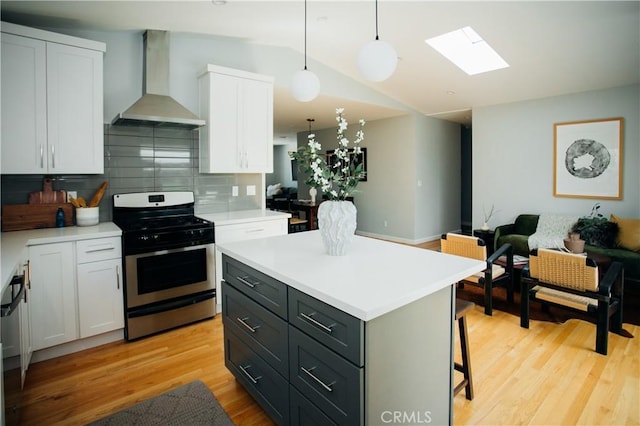17442 Burma St, Encino, CA 91316 - kitchen with wall chimney range hood, stainless steel gas range oven, a skylight, white cabinets, and lofted ceiling
