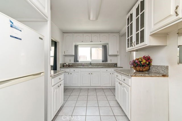 329 N Bushnell Ave, Alhambra, CA 91801 - kitchen featuring white refrigerator, glass insert cabinets, light tile patterned flooring, white cabinets, and light stone countertops