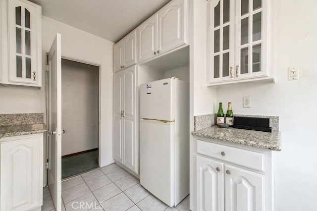 329 N Bushnell Ave, Alhambra, CA 91801 - kitchen with freestanding refrigerator, white cabinetry, glass insert cabinets, light tile patterned flooring, and light stone countertops