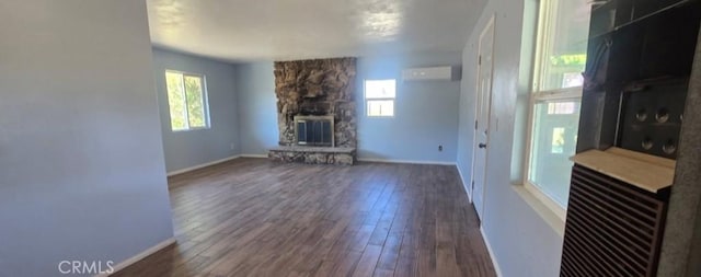 7744 Victor, Yucca Valley, CA 92284 - unfurnished living room with healthy amount of natural light, a fireplace, dark wood-style floors, and a wall mounted air conditioner