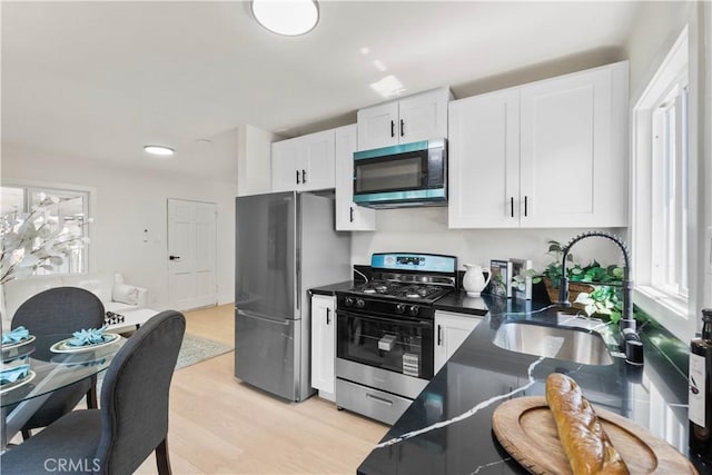 3024 Carl St, Riverside, CA 92507 - kitchen featuring appliances with stainless steel finishes, dark countertops, white cabinets, and light wood-style floors