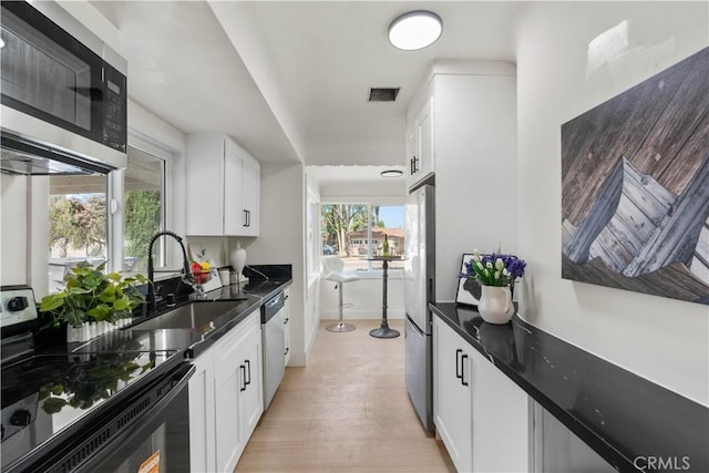 3024 Carl St, Riverside, CA 92507 - kitchen featuring stainless steel appliances, white cabinetry, and light wood finished floors