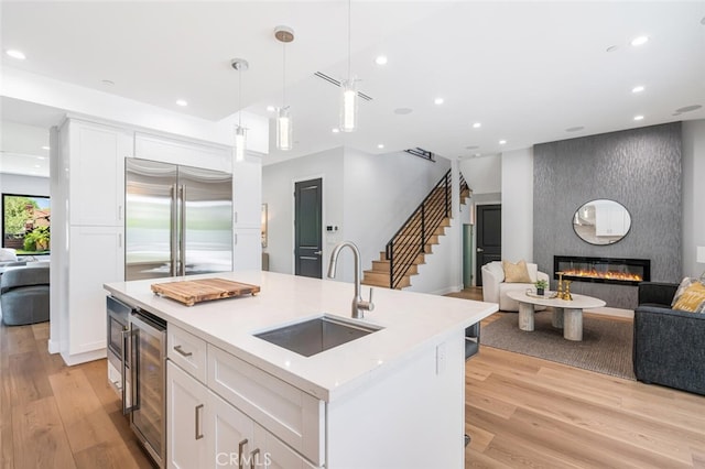 251 S Griffith Park Dr, Burbank, CA 91506 - kitchen with built in appliances, open floor plan, white cabinetry, a large fireplace, and light wood-style flooring