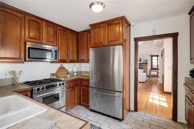 525 Manhattan Beach Blvd, Manhattan Beach, CA 90266 - kitchen featuring stainless steel appliances, tile counters, and brown cabinets
