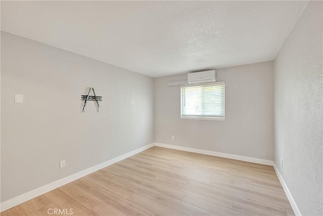 3096 Panorama Rd Unit A, Riverside, CA 92506 - empty room featuring an AC wall unit, light wood-style floors, and a textured ceiling