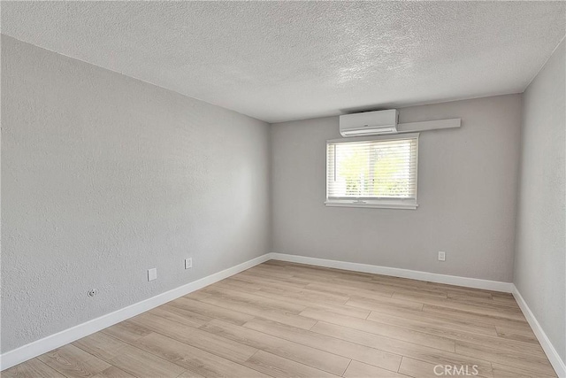 3096 Panorama Rd Unit A, Riverside, CA 92506 - spare room with an AC wall unit, light wood-style flooring, a textured ceiling, and a textured wall