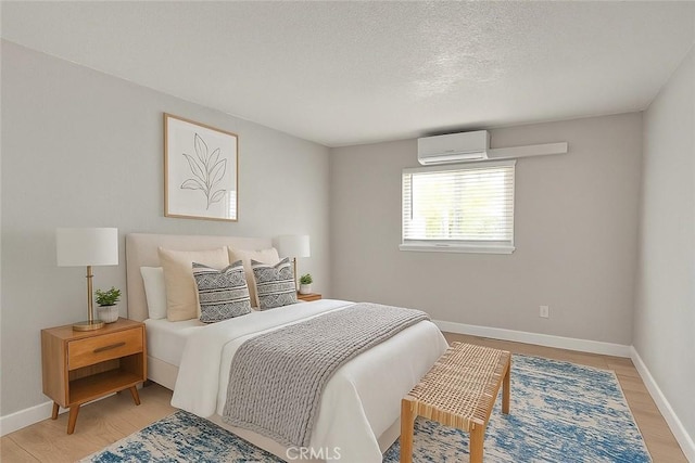 3096 Panorama Rd Unit A, Riverside, CA 92506 - bedroom featuring a wall mounted air conditioner, light wood-type flooring, and a textured ceiling