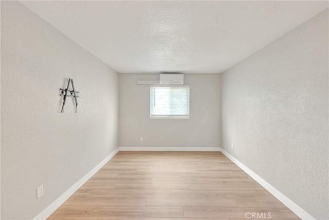3096 Panorama Rd Unit A, Riverside, CA 92506 - unfurnished room with a wall mounted AC, light wood-style floors, a textured wall, and a textured ceiling