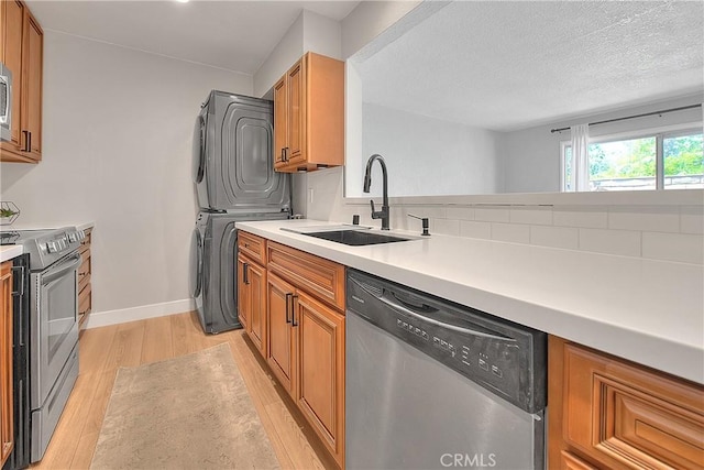 3096 Panorama Rd Unit A, Riverside, CA 92506 - kitchen with stainless steel appliances, stacked washing machine and dryer, light wood-style floors, light countertops, and brown cabinetry