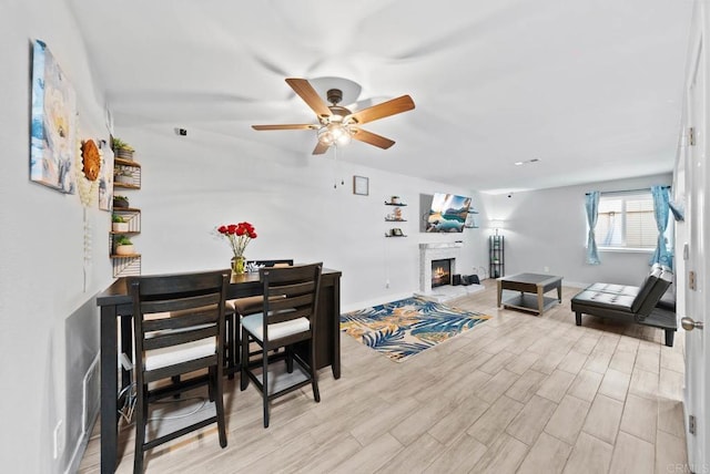 353 61st St, San Diego, CA 92114 - dining space featuring a ceiling fan, a lit fireplace, and light wood-type flooring