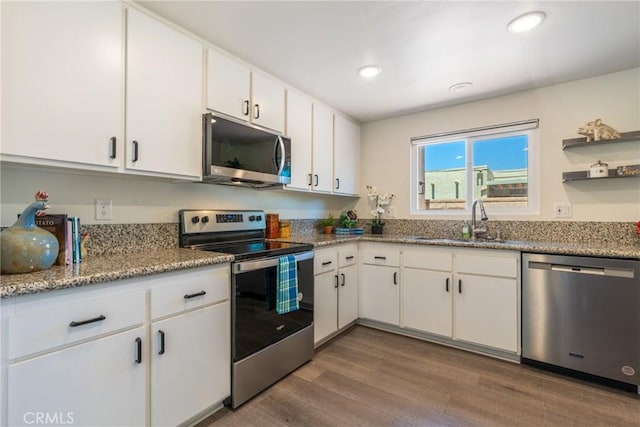 3066 Via Serena S Unit A, Laguna Woods, CA 92637 - kitchen with appliances with stainless steel finishes, wood finished floors, white cabinetry, recessed lighting, and light stone countertops