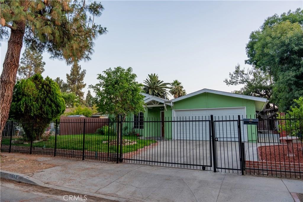 11863 Vanport Ave, Sylmar, CA 91342 - view of front facade featuring a garage, concrete driveway, a fenced front yard, and stucco siding