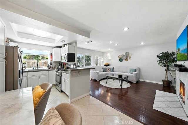 1465 E Lexington Ave Unit 4C, El Cajon, CA 92019 - kitchen featuring appliances with stainless steel finishes, open floor plan, white cabinetry, light tile patterned floors, and recessed lighting