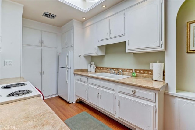 2205 Via Mariposa E Unit A, Laguna Woods, CA 92637 - kitchen with white appliances, white cabinets, light wood finished floors, recessed lighting, and light countertops