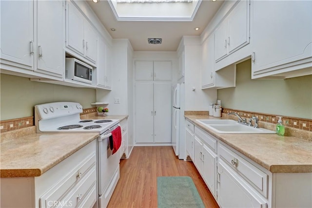 2205 Via Mariposa E Unit A, Laguna Woods, CA 92637 - kitchen with white appliances, light wood-style floors, backsplash, white cabinets, and light countertops