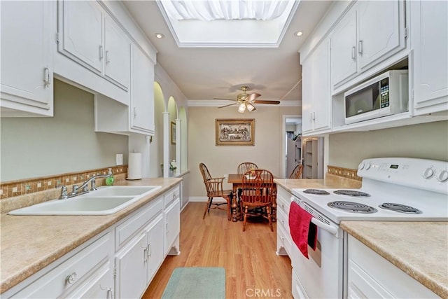 2205 Via Mariposa E Unit A, Laguna Woods, CA 92637 - kitchen with white electric stove, built in microwave, white cabinetry, light countertops, and crown molding