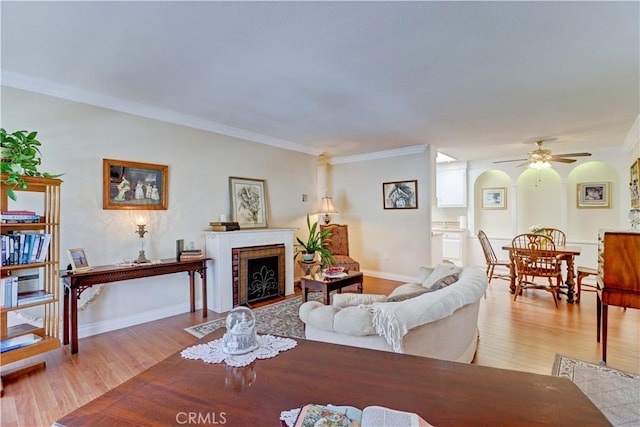 2205 Via Mariposa E Unit A, Laguna Woods, CA 92637 - living room featuring light wood-style flooring, a ceiling fan, a fireplace, and ornamental molding