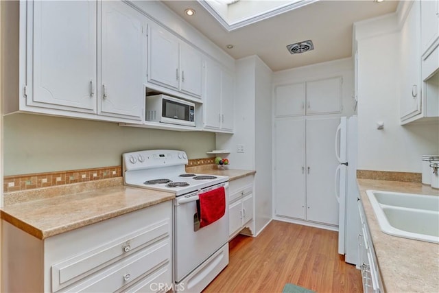 2205 Via Mariposa E Unit A, Laguna Woods, CA 92637 - kitchen featuring white appliances, light countertops, white cabinetry, light wood finished floors, and recessed lighting