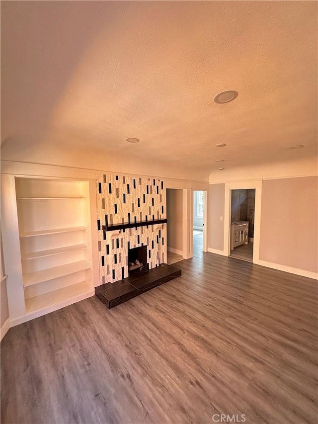 696 E 51st St E, Los Angeles, CA 90011 - unfurnished living room featuring wood finished floors, a textured ceiling, built in features, and a fireplace