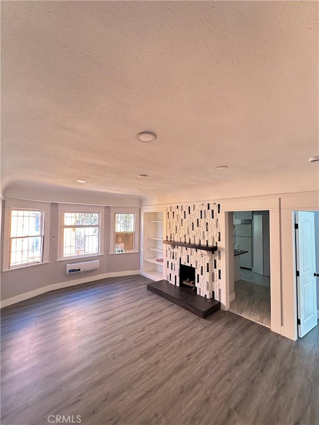 696 E 51st St E, Los Angeles, CA 90011 - unfurnished living room featuring a textured ceiling, dark wood-style flooring, plenty of natural light, a wall mounted air conditioner, and a fireplace