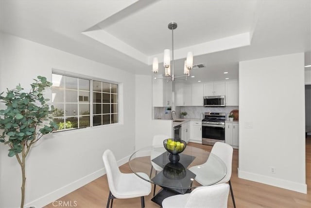 4455 Hazeltine Ave Unit 103, Sherman Oaks, CA 91423 - dining space featuring a raised ceiling, light wood-type flooring, and a chandelier