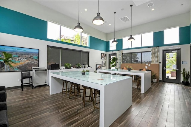 5140 Calle Sand Arch Unit 61, San Diego, CA 92154 - kitchen with a towering ceiling, dark wood finished floors, a kitchen island, light countertops, and a breakfast bar area