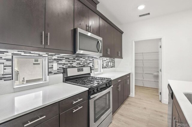 5140 Calle Sand Arch Unit 61, San Diego, CA 92154 - kitchen featuring stainless steel appliances, light wood-type flooring, light countertops, dark brown cabinetry, and decorative backsplash