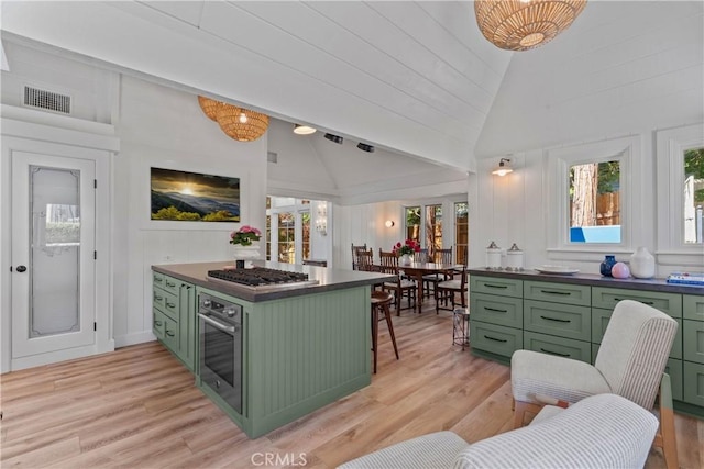 28233 N Shore Rd, Lake Arrowhead, CA 92352 - kitchen with green cabinetry, appliances with stainless steel finishes, light wood-style floors, dark countertops, and high vaulted ceiling