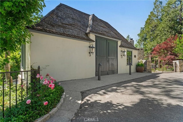 28233 N Shore Rd, Lake Arrowhead, CA 92352 - back of house featuring stucco siding, a gate, and a chimney
