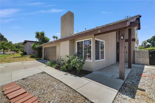 5005 Pearblossom Dr, Riverside, CA 92507 - view of property exterior featuring stucco siding, concrete driveway, an attached garage, and a chimney