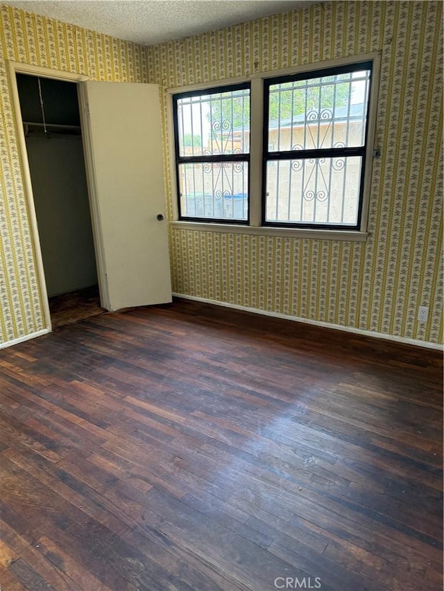1317 S Baker St, Santa Ana, CA 92707 - unfurnished bedroom with wallpapered walls, wood finished floors, a closet, and a textured ceiling