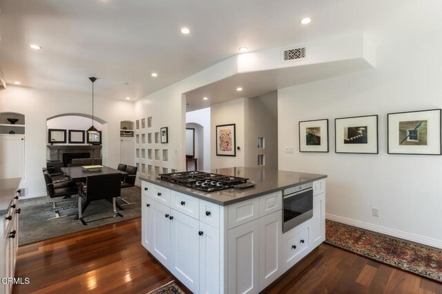 1040 Hillcroft Rd, Glendale, CA 91207 - kitchen featuring gas stovetop, arched walkways, dark wood-style flooring, a fireplace, and white cabinetry