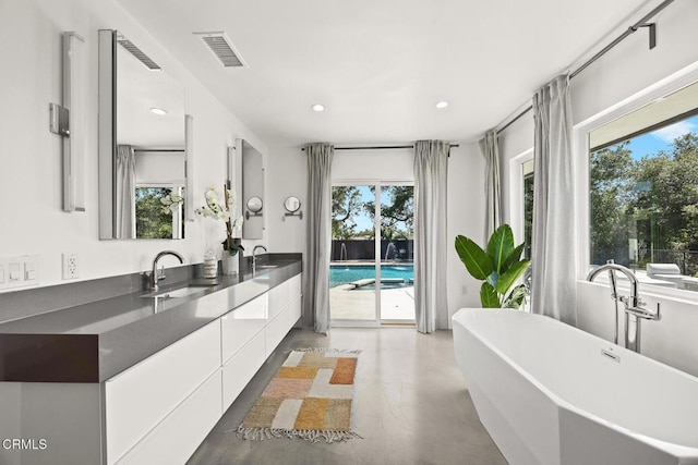 1305 Riviera Dr, Pasadena, CA 91107 - full bath with finished concrete floors, double vanity, plenty of natural light, a freestanding tub, and recessed lighting