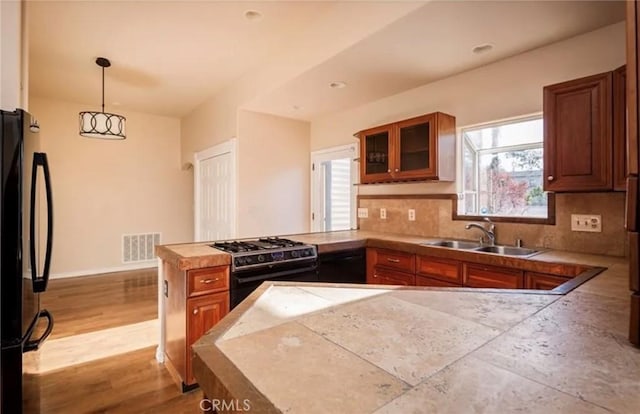 1263 Pismo St, San Luis Obispo, CA 93401 - kitchen with black appliances, a peninsula, brown cabinets, glass insert cabinets, and decorative backsplash