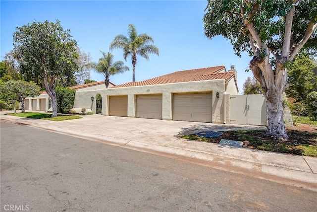 5490 Paseo Del Lago W Unit P, Laguna Woods, CA 92637 - view of front of house featuring a garage, a tiled roof, driveway, stucco siding, and a chimney