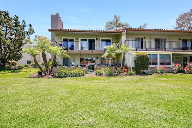 5490 Paseo Del Lago W Unit P, Laguna Woods, CA 92637 - rear view of property with a chimney, a yard, stucco siding, and a balcony