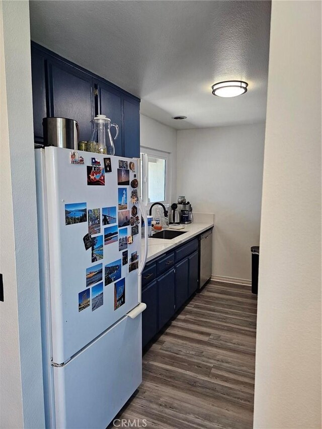 874 Cinnamon Ln Unit 62, Duarte, CA 91010 - kitchen with freestanding refrigerator, stainless steel dishwasher, blue cabinets, dark wood-style flooring, and light countertops