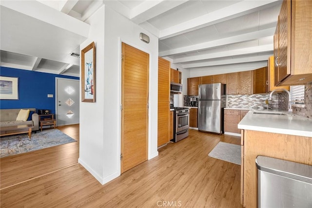 18101 Kirk Ave, Tustin, CA 92780 - kitchen featuring appliances with stainless steel finishes, beam ceiling, light wood finished floors, brown cabinetry, and light countertops