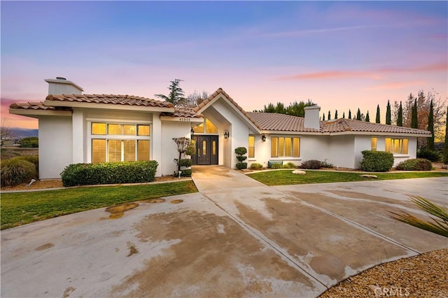 41901 Calle Clarita, Lancaster, CA 93536 - view of front of house featuring a chimney, stucco siding, a tiled roof, and a lawn