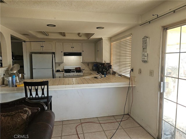16709 Deodar St, Hesperia, CA 92345 - kitchen featuring white appliances, tile counters, under cabinet range hood, decorative backsplash, and a peninsula
