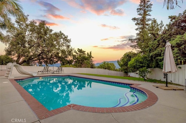 3326 Los Olivos Ln, Glendale, CA 91214 - pool at dusk featuring a water slide, a fenced backyard, and a patio